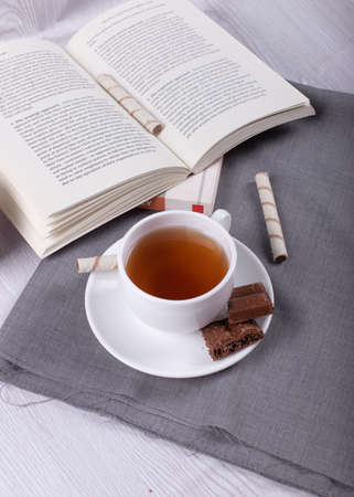 Book, cup of tea and chocolate on the tableの写真素材