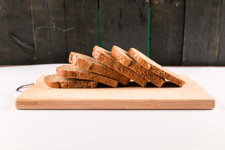 Dark bread slices on a wooden board isolated on black backgroundの写真素材