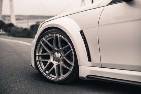 Front wheel of a white sedan car parked on the road