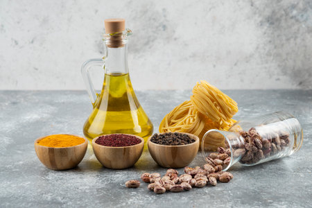 A glass jar with raw white kidney beans and raw nest pasta on a gray backgroundの写真素材