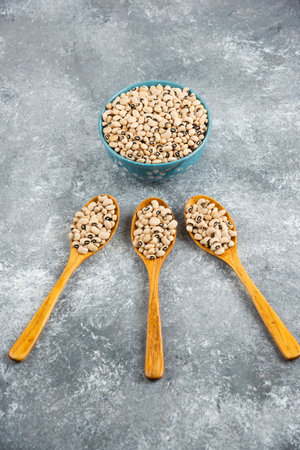A bowl full of white raw kidney beans with wooden spoons