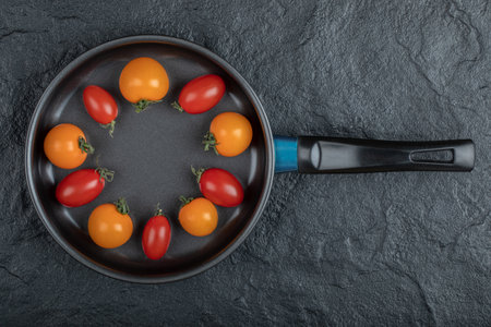 Colorful fresh cherry tomatoes in the pan on black backgroundの写真素材