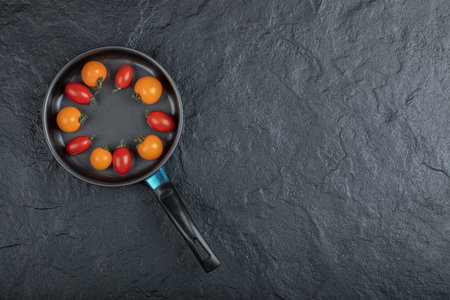 Black frying pan full of cherry tomatoes