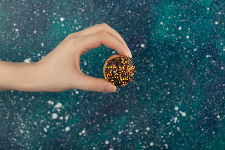 Woman hand holding a small chocolate doughnut
