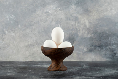 Bowl of white eggs on marble background