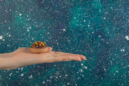 Female hand holding cookie on colorful background