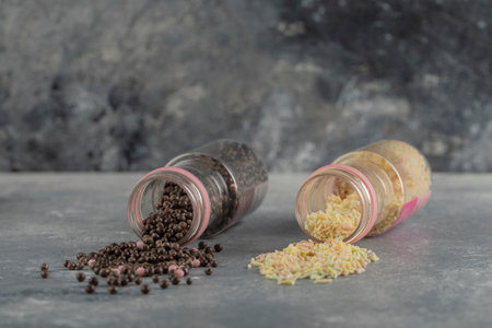 Two bottles of colorful sprinkle dotes on a marble backgroundの写真素材