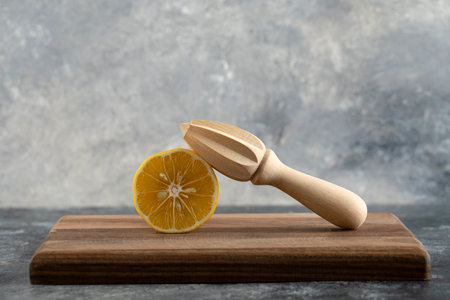 Sliced lemon with a wooden reamer on a wooden boardの写真素材