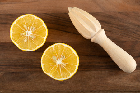 Sliced lemon with a wooden reamer on a wooden table