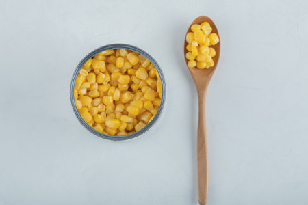 A wooden spoon full of popcorn seeds on a white backgroundの写真素材
