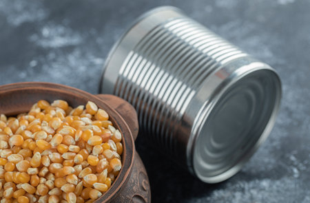 An ancient bowl full of uncooked popcorn seeds with metallic can