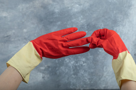 Hands wearing red protective gloves on marble backgroundの写真素材