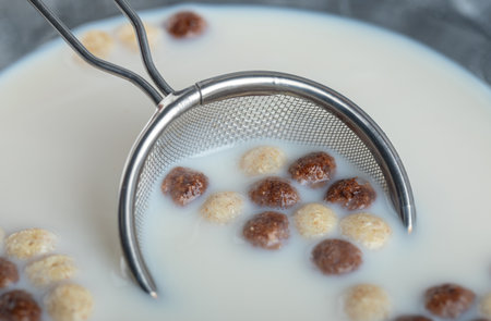 Sweet cereal balls and bowl of milk on marble background