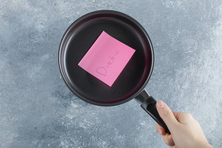 Woman hand holding a pan with pink stickerの写真素材