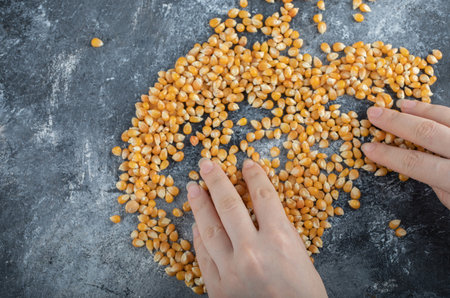 Hand distributing uncooked popcorn seeds on a marble backgroundの写真素材