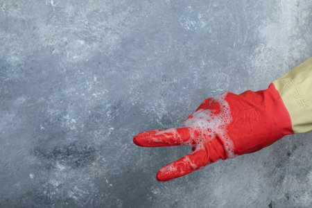 Hand in red protective gloves on marble backgroundの写真素材