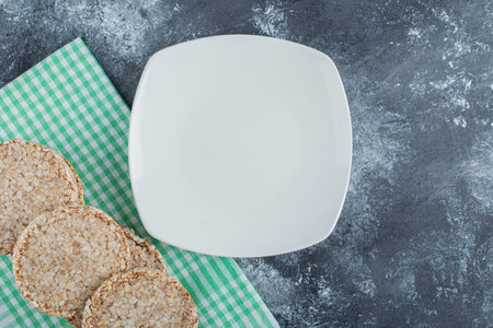 An empty white plate with crispy rice bread on a marble backgroundの写真素材
