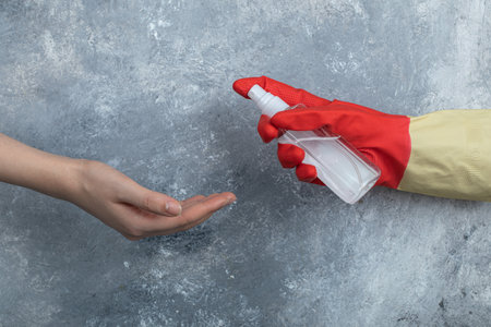 Hand in protective gloves spraying ethanol to womanの写真素材