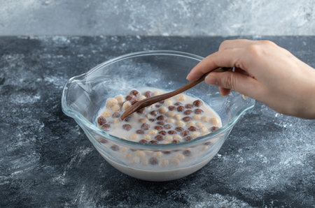 Female hand holding spoon of chocolate balls on marble background