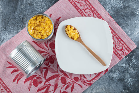 A wooden spoon of popcorn seeds on an empty plate