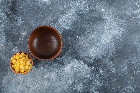 An empty wooden bowl with small bowl of popcorn seedsの写真素材