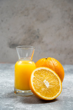 A glass jar of orange juice and sliced orangeの写真素材
