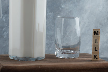Jug of milk and glass of water on wooden boardの写真素材