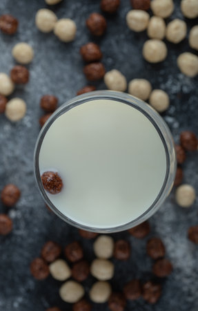 Bunch of cereal balls scattered around glass of fresh milk