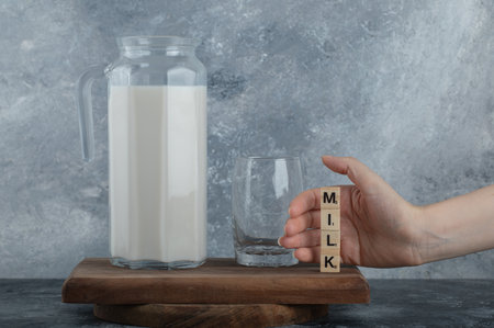Female hands holding wooden letters with fresh milkの写真素材