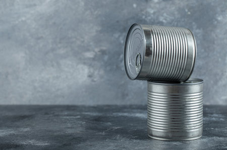 Closed tin cans with vegetables placed on marble backgroundの写真素材