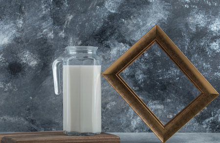 Jug of fresh milk and picture frame on marble backgroundの写真素材