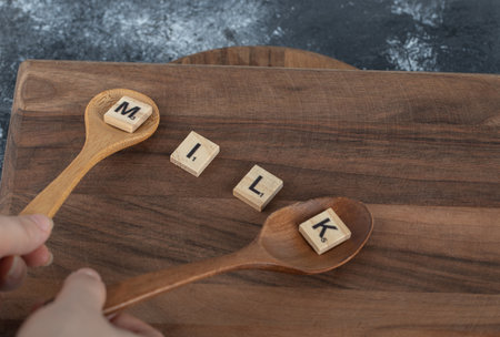 Hands holding spoon of wooden letters on wooden boardの写真素材
