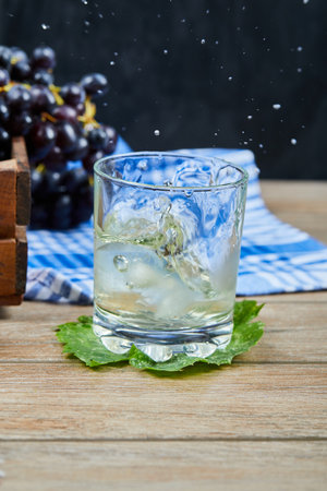 A glass of white wine on a wooden table with grapesの写真素材