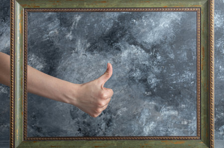 female hand giving thumbs up with male in middle of picture frameの写真素材
