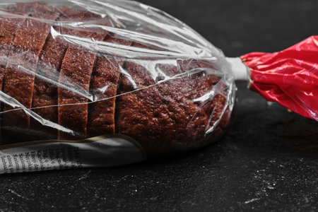 Sliced black rye bread in plastic bag on dark backgroundの写真素材