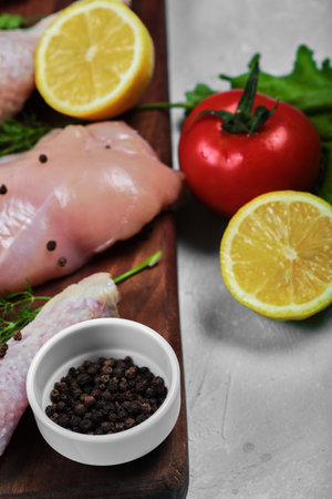 Raw chicken fillet and legs on wooden plate with fresh vegetables. Close upの写真素材