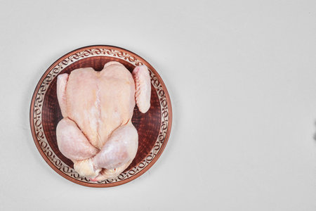 Raw whole chicken on ceramic plate isolated on white backgroundの写真素材