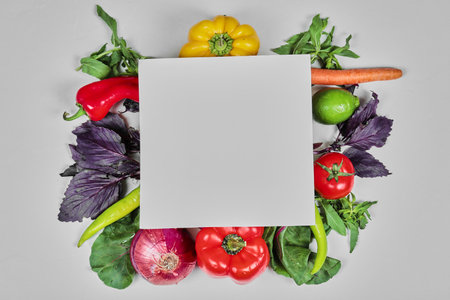 Fresh vegetables, carrots, peppers, greens, carrots, onion around white paperの写真素材