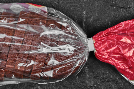 Sliced black rye bread in plastic bag on dark backgroundの写真素材