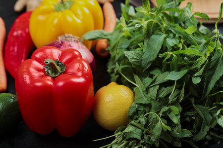 Close up colorful fresh peppers, lemon and greens on tableの写真素材