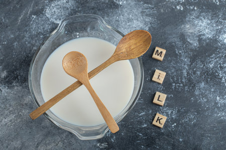 Bowl of milk and wooden letters spelled as milkの写真素材