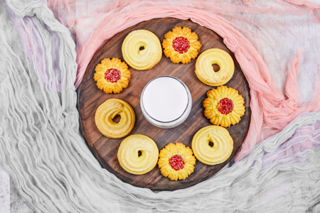 Assorted biscuits and a jar of milk on a wooden plate with tablecloths. High quality photoの写真素材