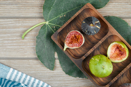 Figs in a wooden platter on the green leavesの写真素材