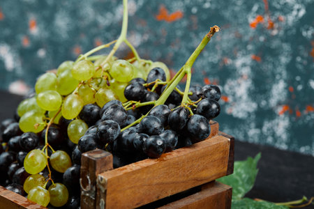 Green and red wine bunches in a wooden trayの写真素材