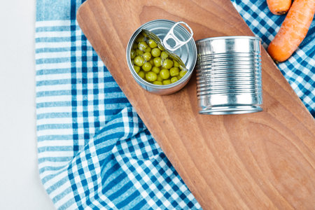 Two cans of boiled green peas, vegetables and tablecloth on a white backgroundの写真素材