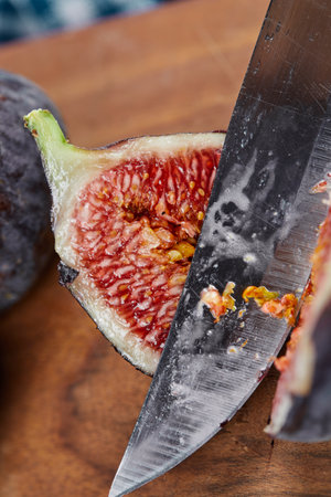 Cutting a fig on a wooden cutting board with a blue tableclothの写真素材