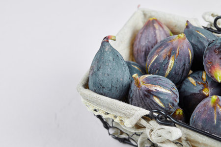 A basket of purple figs on a white background