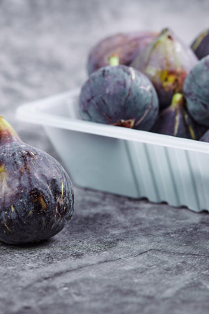 Purple figs in a white plastic containerの写真素材