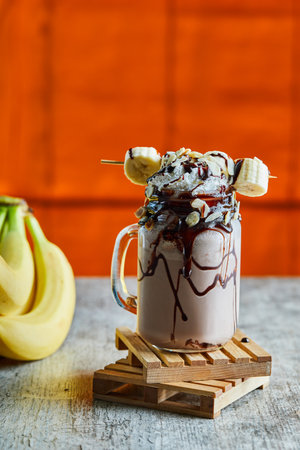 Chocolate smoothie with choco syrup and branch of bananasの写真素材