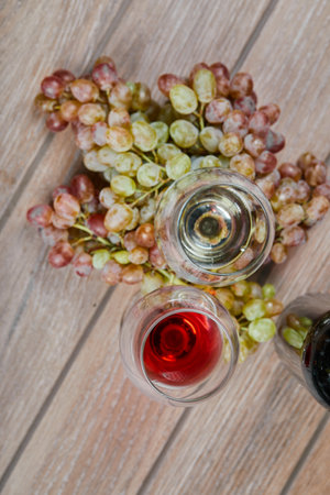 A glass of red wine with a bunch of green grapes aroundの写真素材